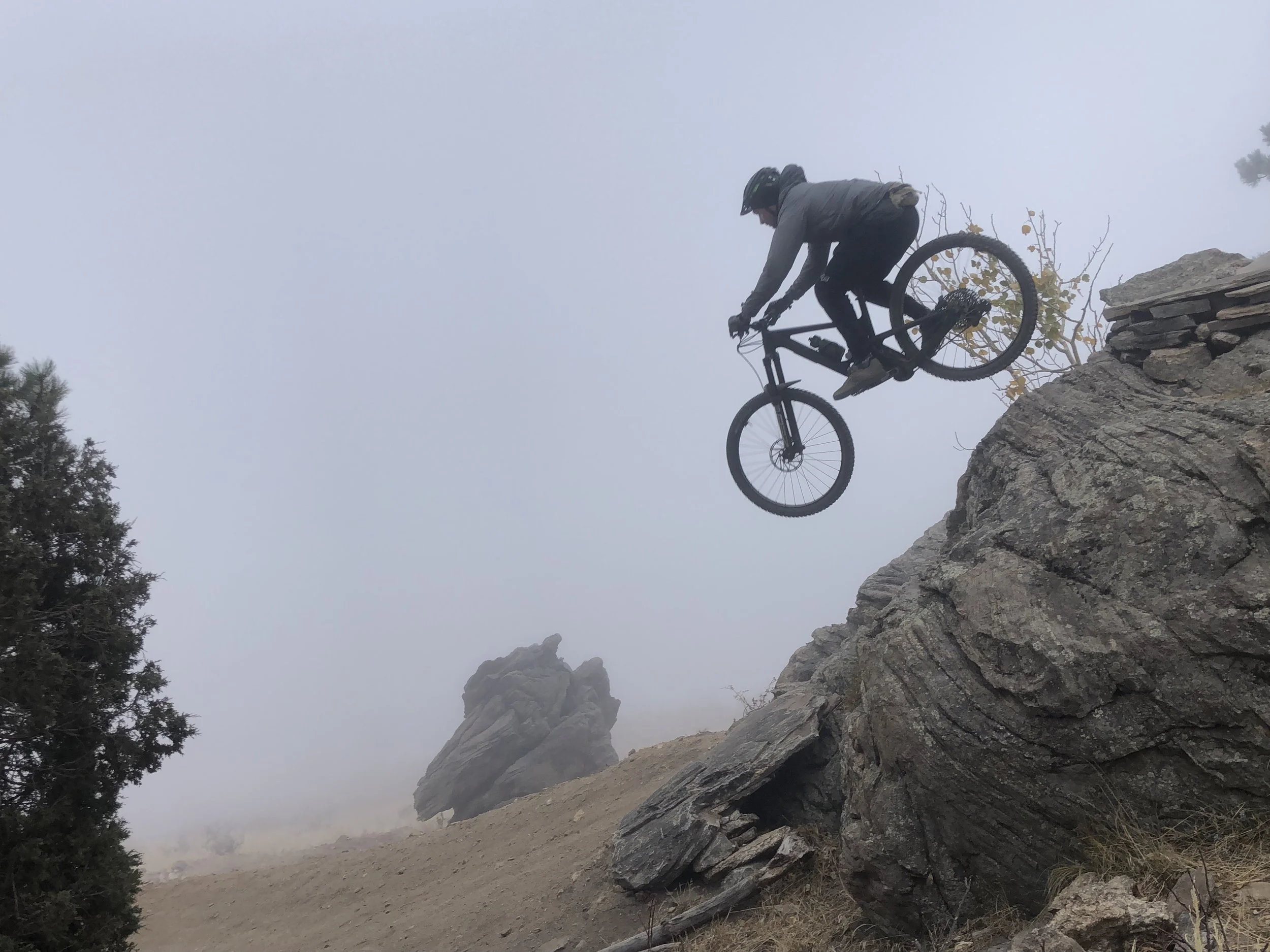 Dropping off a rock in the fog on a Colorado mountain-bike trail.